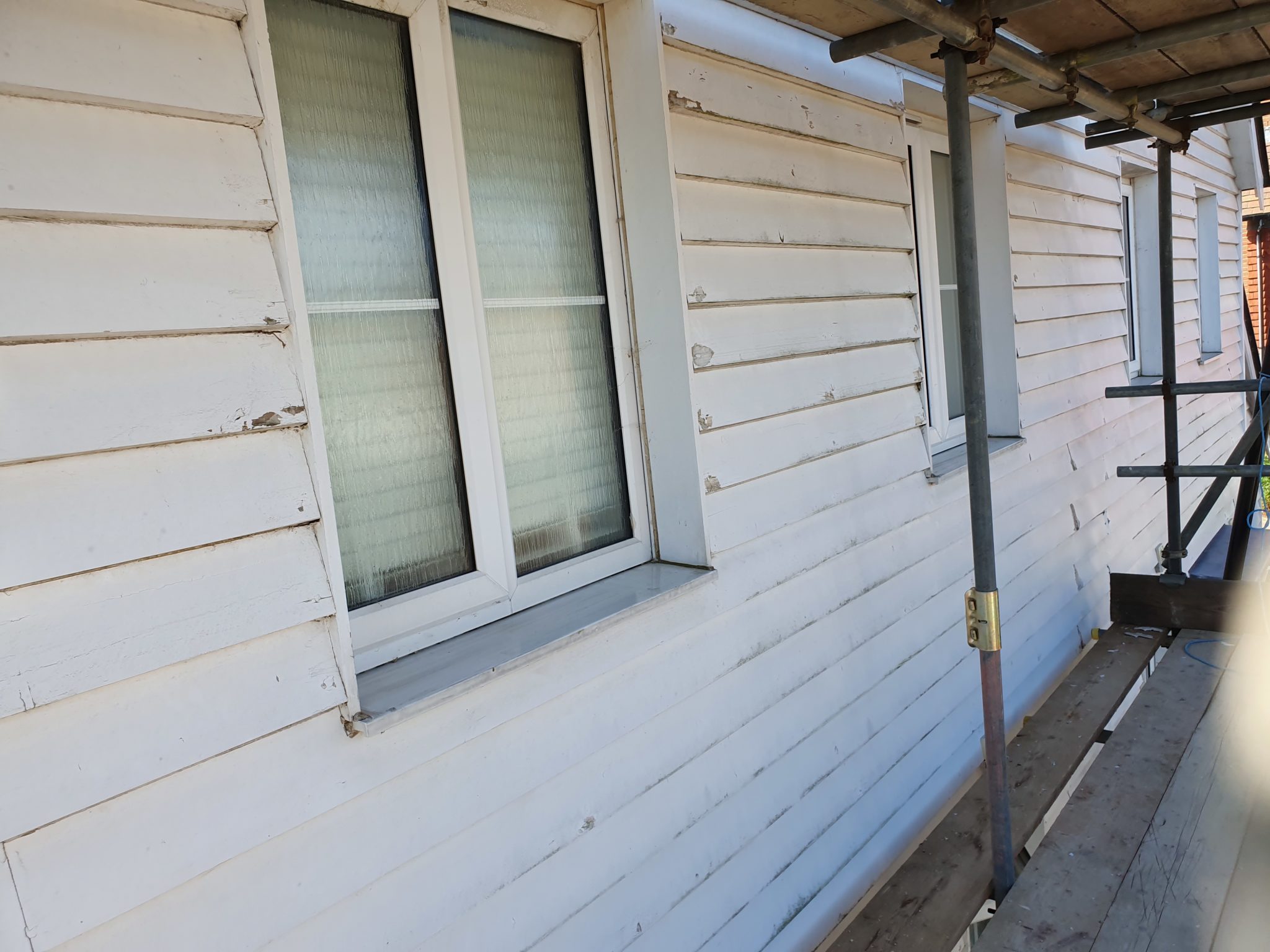 Weatherboarding being repainted white around a window