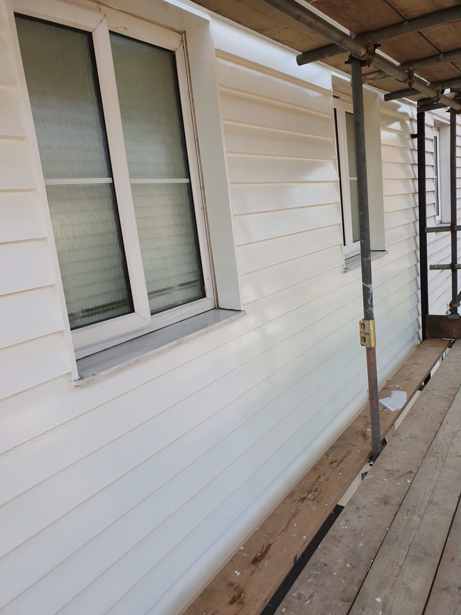 White weatherboarding and window under scaffolding