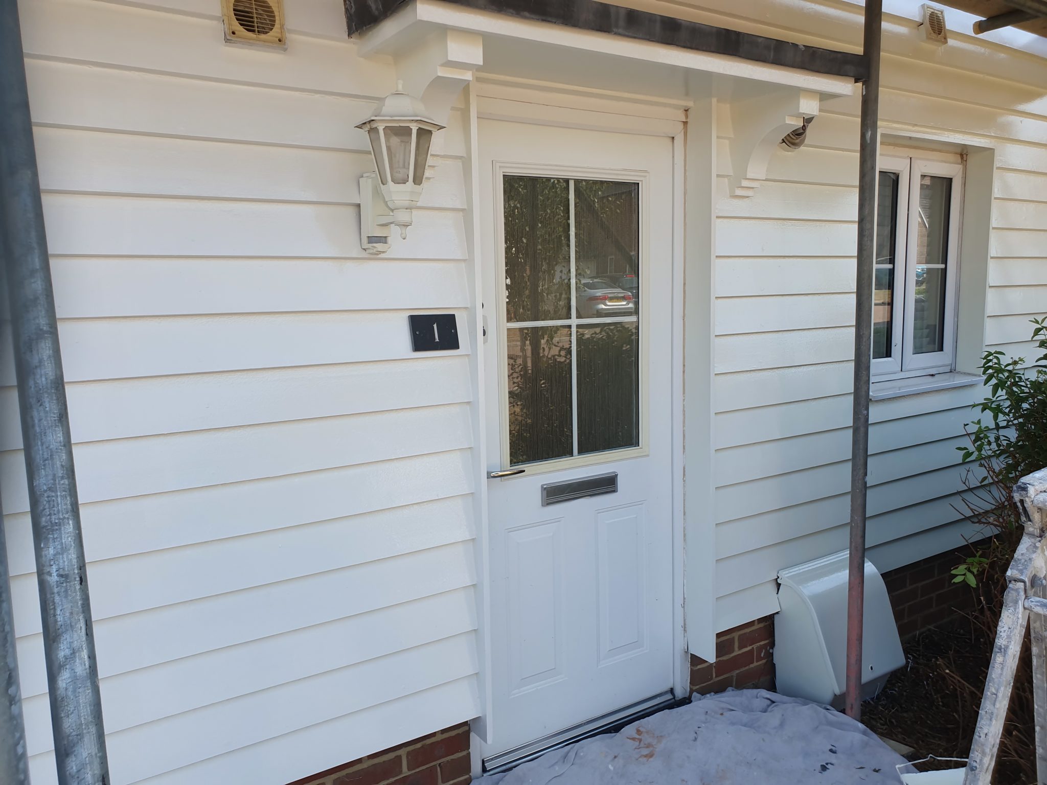 White painted weatherboarded bungalow with a white front door