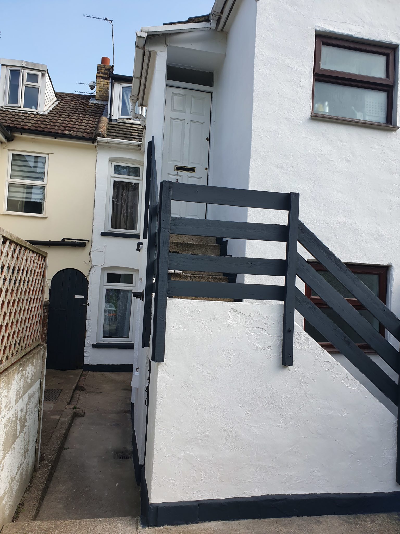 White rendered steps and wall with dark grey railings