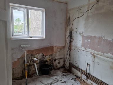 Kitchen wall stripped back to brick and old plaster, with pipework showing