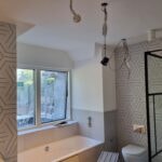 Bathroom part way through a refit, with patterned tiles and the bath in place