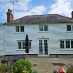 White weatherboarded house with white windows under a slate roof