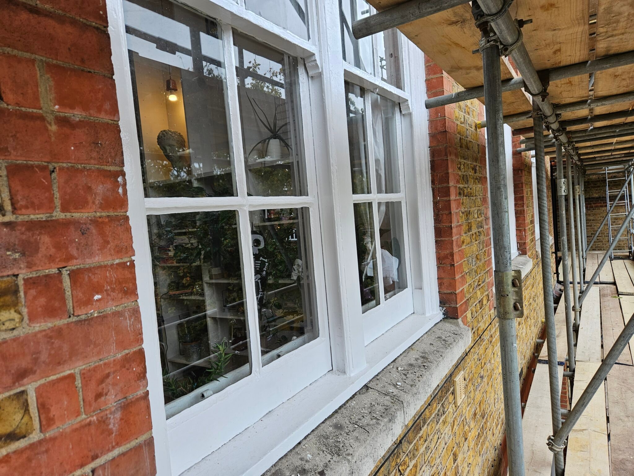 White painted timber windows behind scaffolding poles