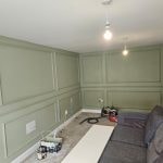 Living room with sage green panelled walls and a white ceiling